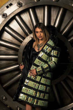 Young woman posing in front of industrial vault door wearing a winter coat lined with 20 dollar Canadian bills